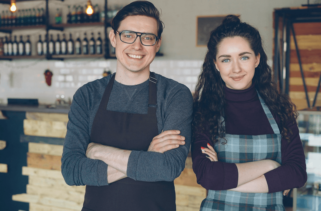 Local business owners smiling behind the counter of their café, representing Worthify’s commitment to strengthening customer relationships.