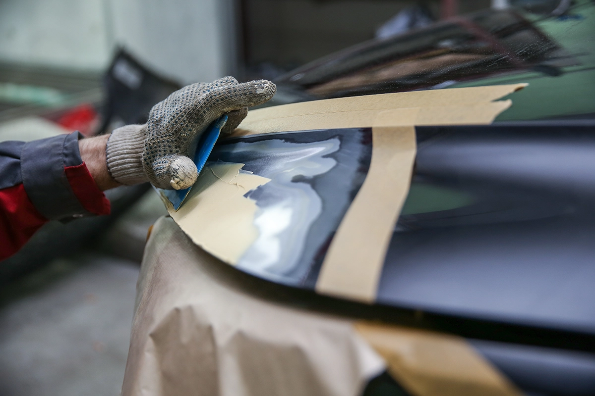 Technician reshaping a fender of a car.