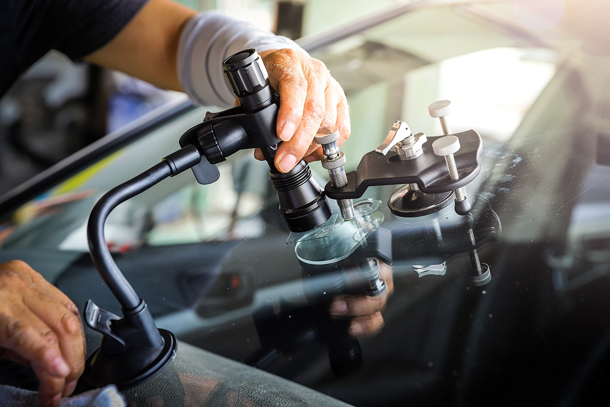 A technician repairing a cracked windshield with a specialized tool.