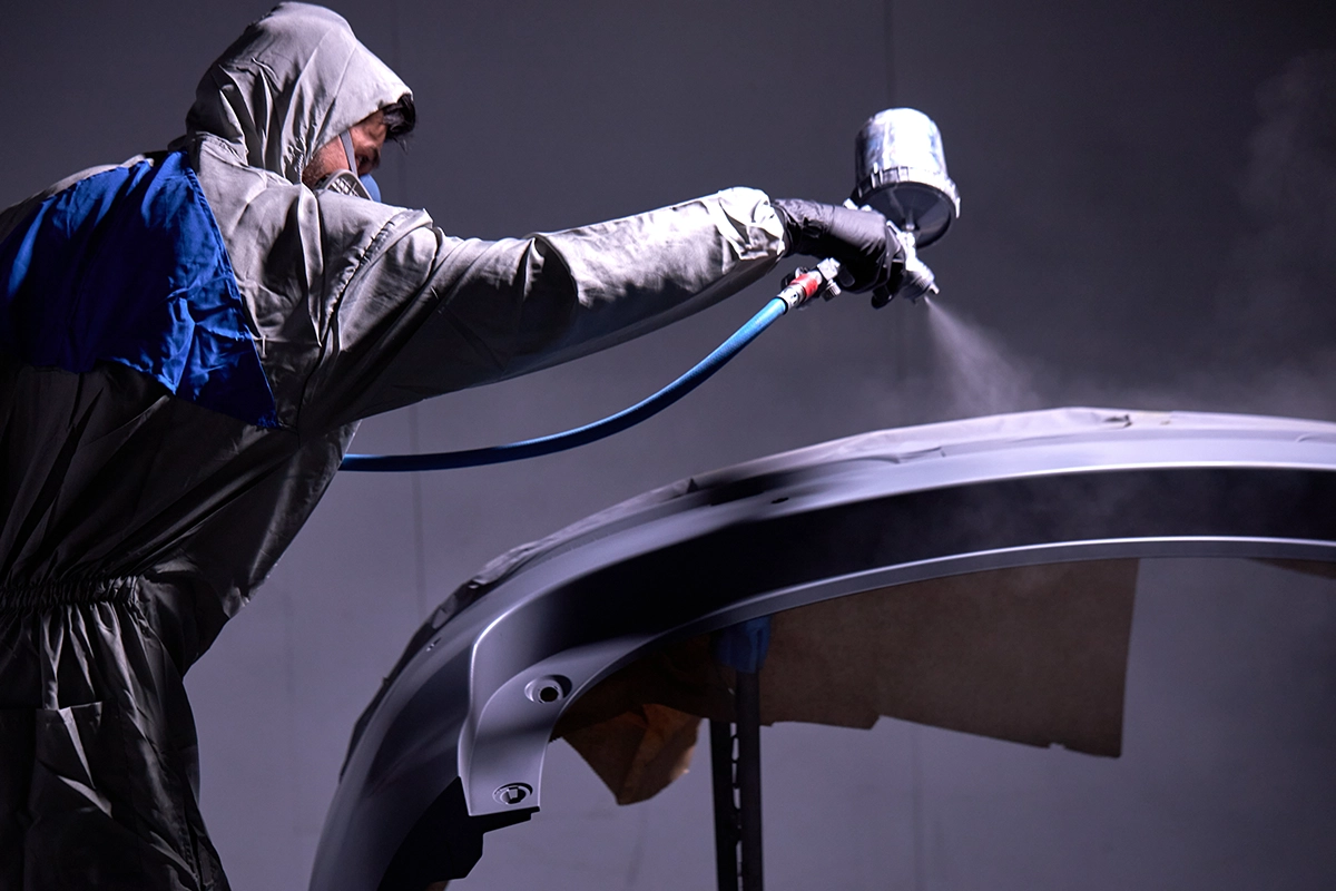 Technician painting an auto body part.