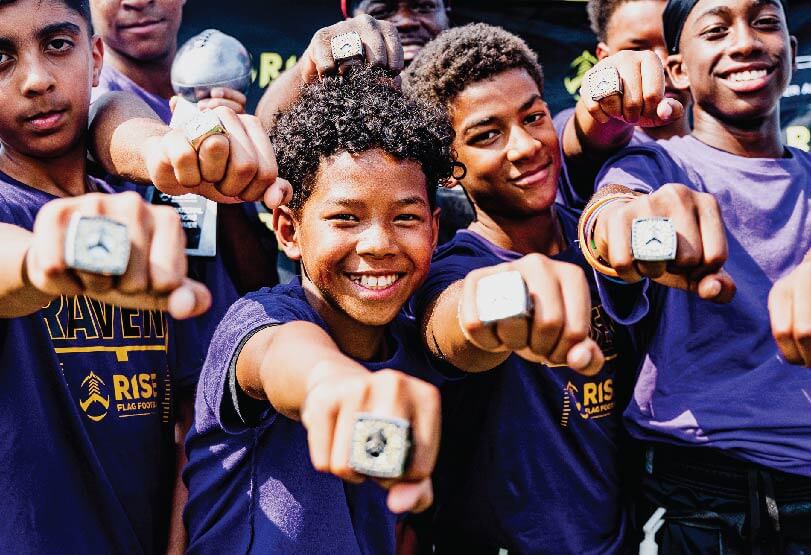 Team players showing off their RISE flag football championship rings 