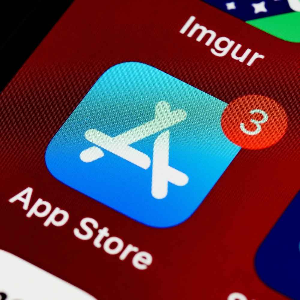 Close-up of an iPhone screen showing App Store icon with three notification badges.