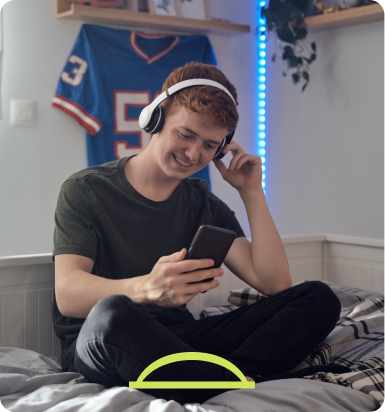 A man wearing headphones and looking at a cell phone. - Hopscotch Images