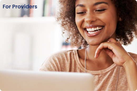 A woman smiling while using a laptop. - Hopscotch Images