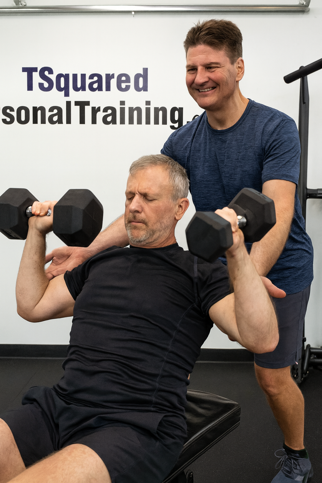 Fit personal trainer in Vancouver guiding a middle-aged male client through small group strength training for men over 40 at Tsquared Personal Training.