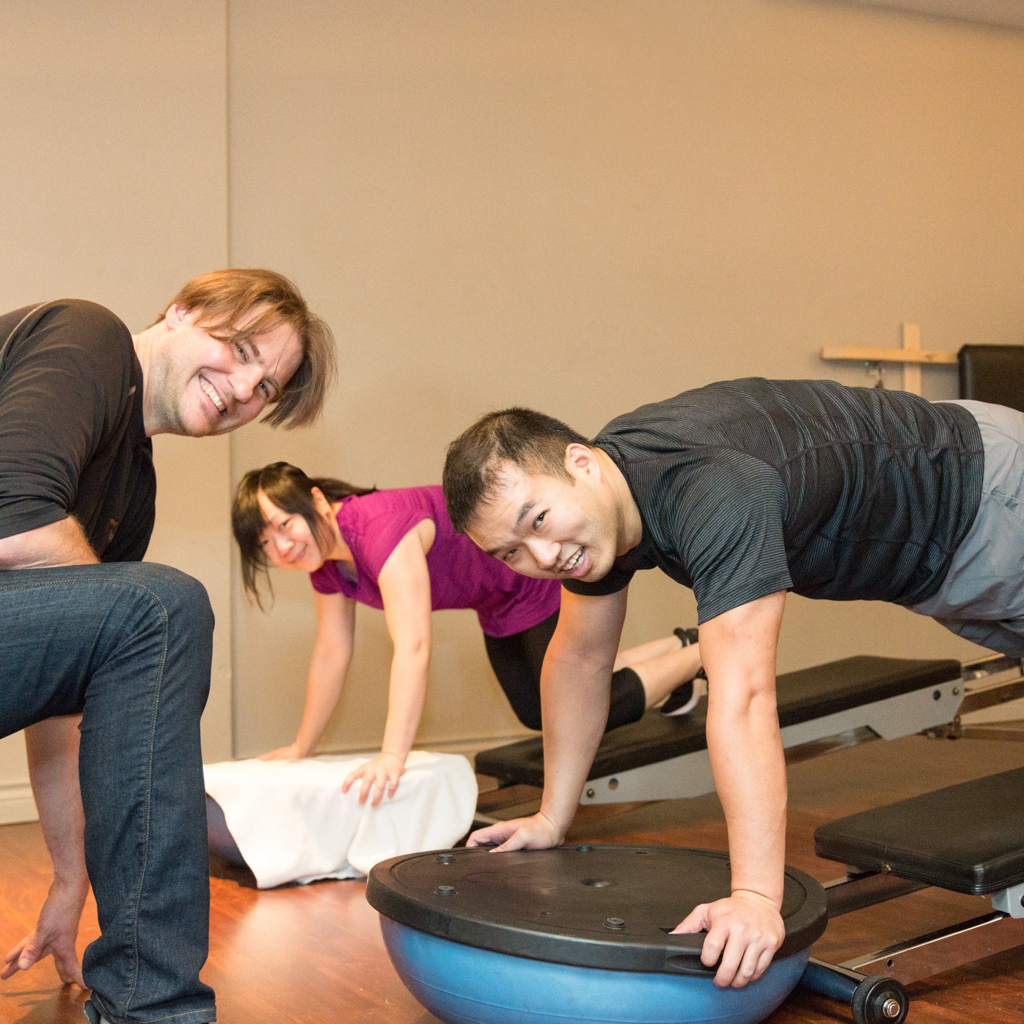 Personal trainer in Downtown Vancouver guiding a small group through core strength exercises on stability balls and mats at Tsquared Personal Training studio.