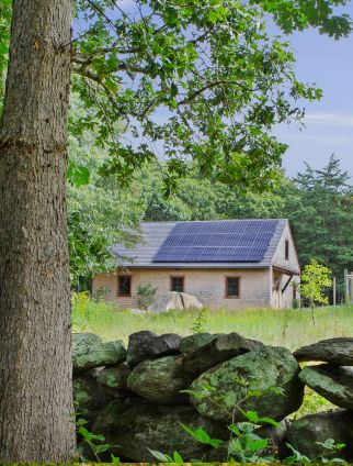 A barn in a field with solar panels on the roof.