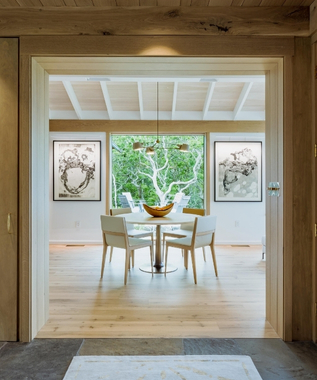 A dining room with a round table, four chairs and art on the walls inside a South Mountain Company house.