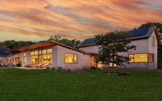 A new South Mountain Company house set in a West Tisbury meadow with a beautiful sunset.