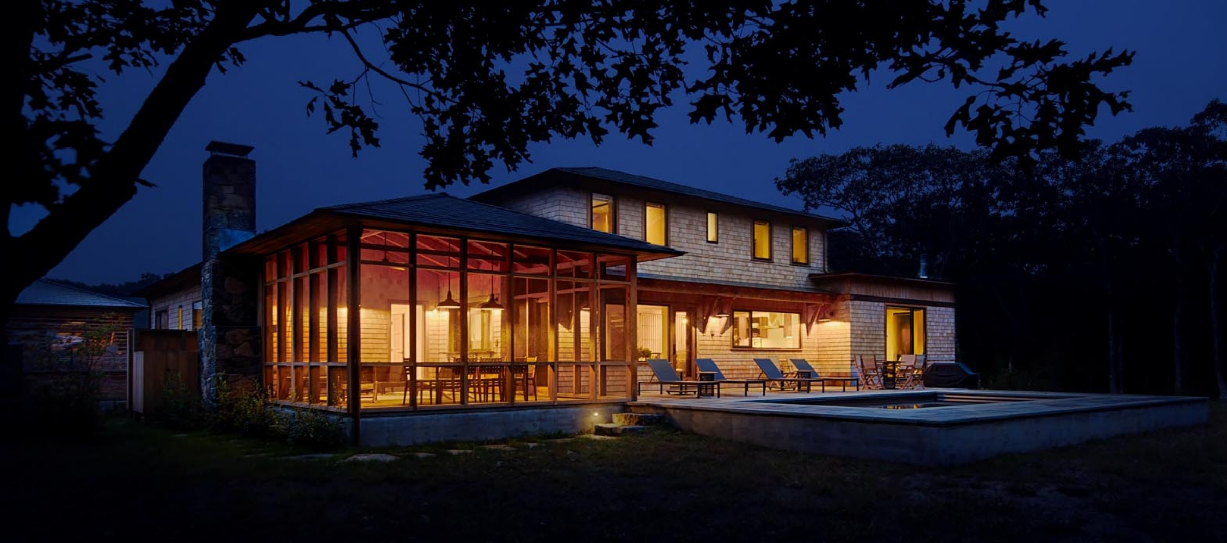West Tisbury South Mountain Company house glowing at dusk with lights on inside.