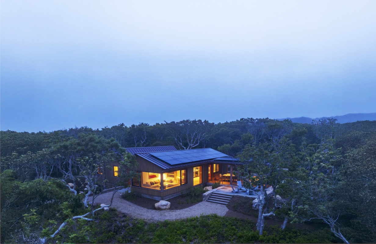 Aerial view of South Mountain Company house overlooking Vineyard Sound public spaces with solar on the roof, taken at dusk.