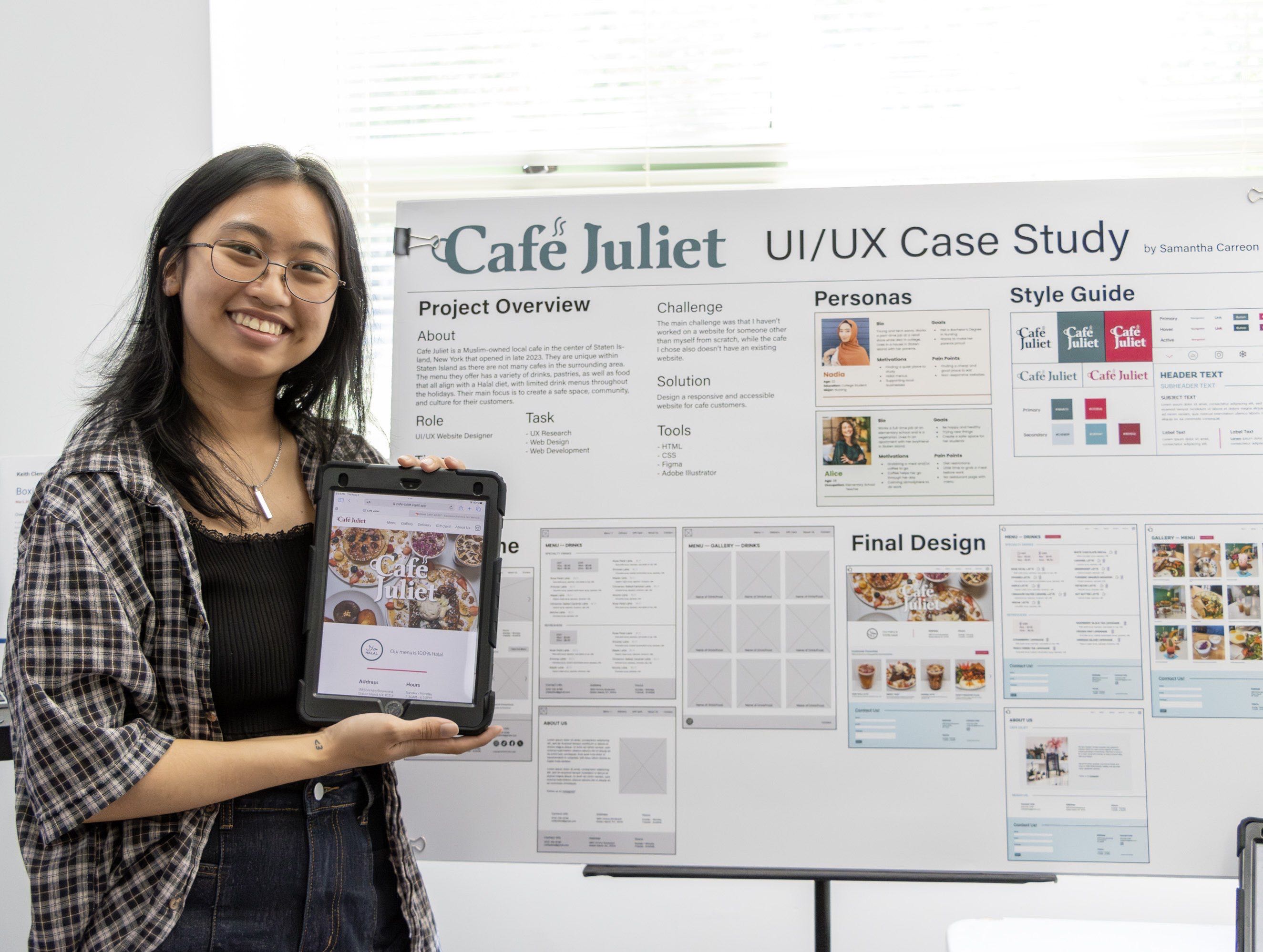 Sam smiling while holding a tablet displaying Cafe Juliet's website standing in front of a posterboard that shows the design process for the site.