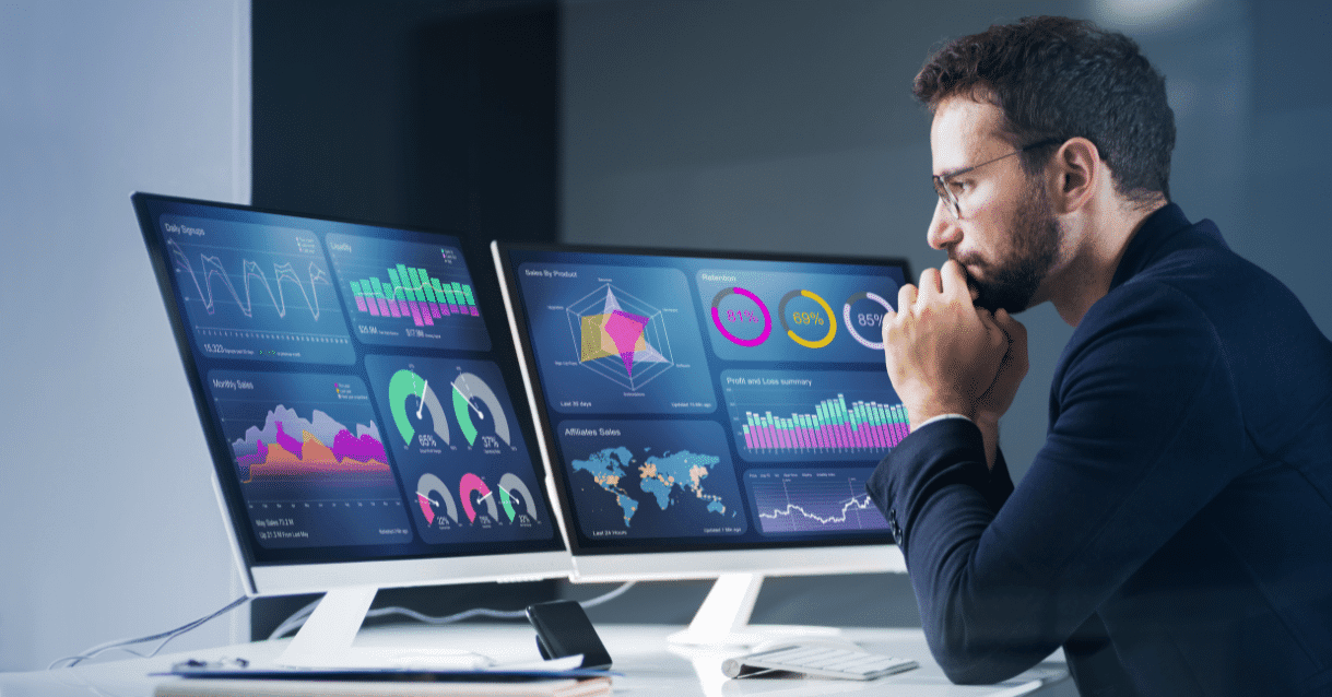 Man looking at computer screens with analytics