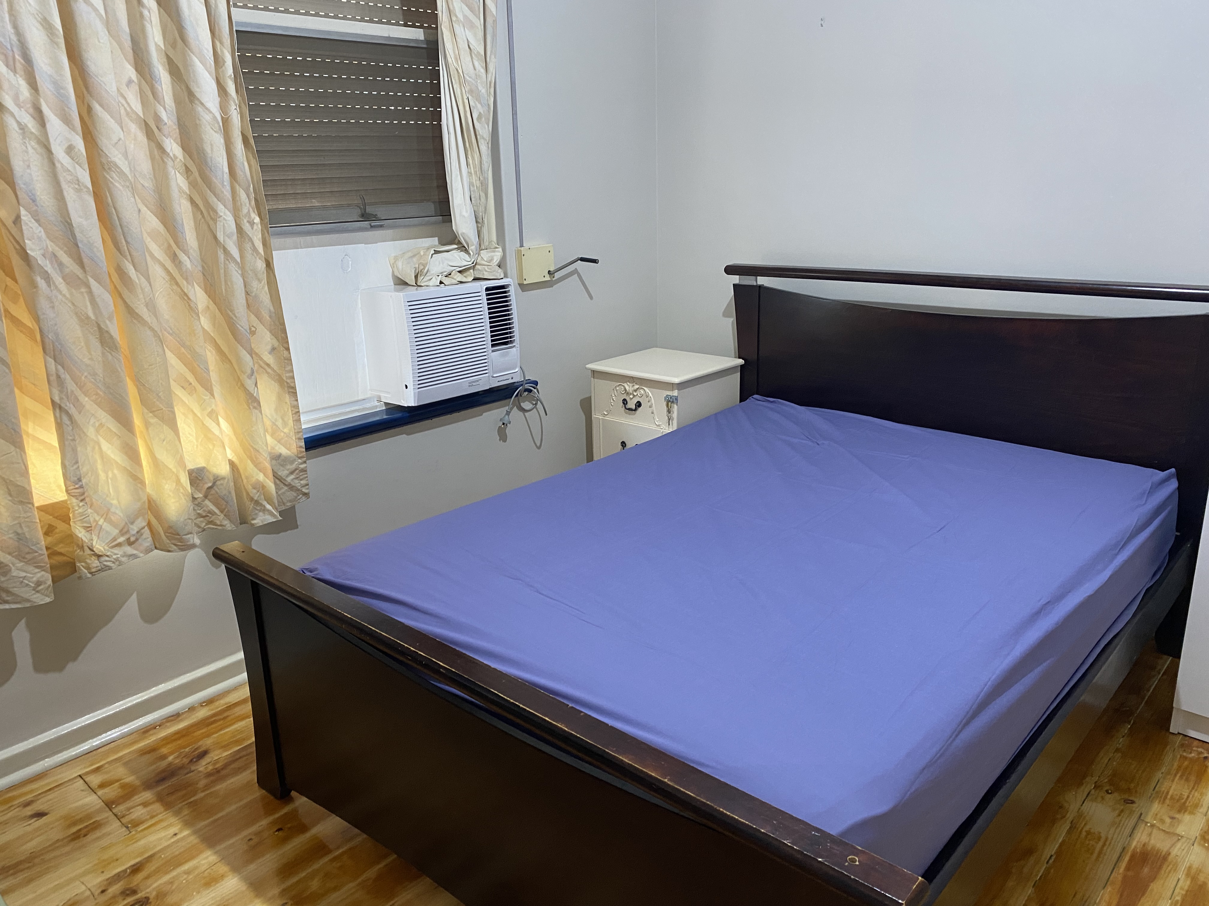 Furnished bedroom with bed, side table and window curtains
