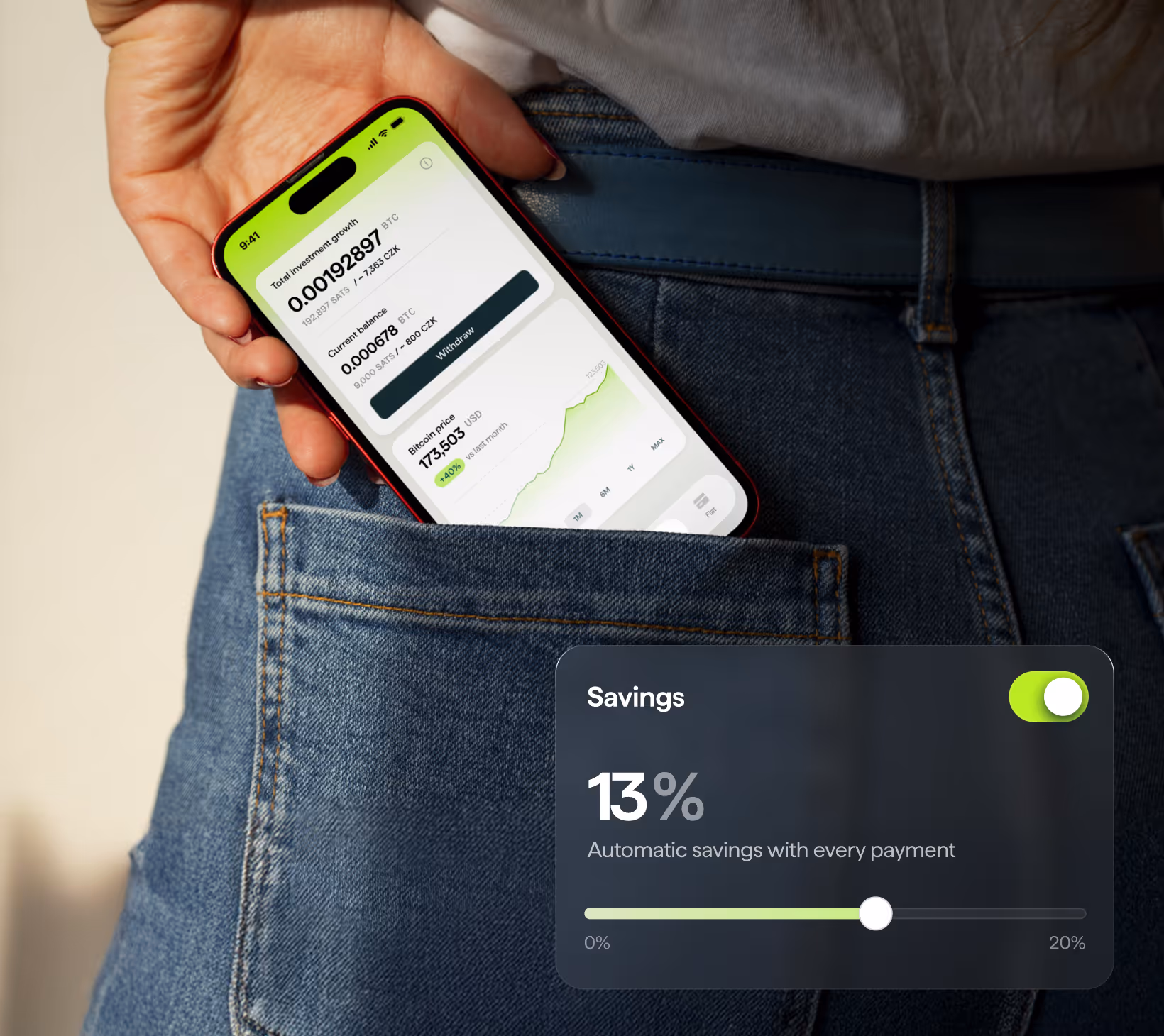 Hand holding a smartphone showing bitcoin investment details and a savings feature indicating 13% automatic savings with every payment.