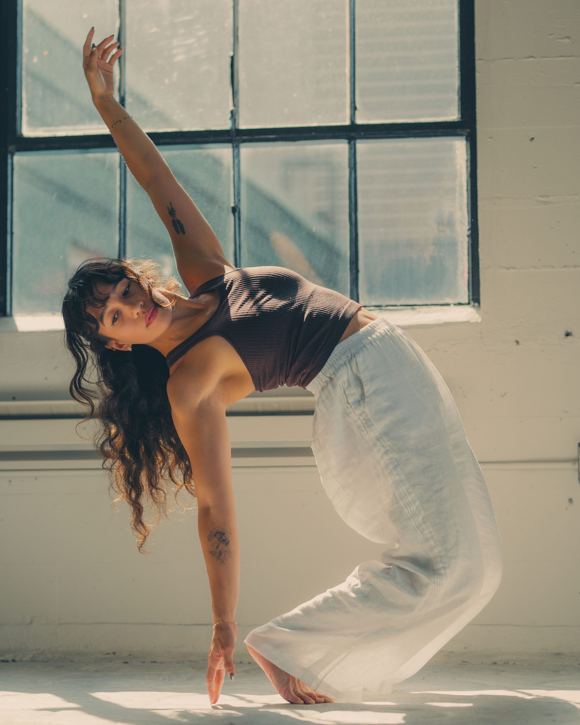 Iza Narag arching into a standing backbend in a sunlit studio