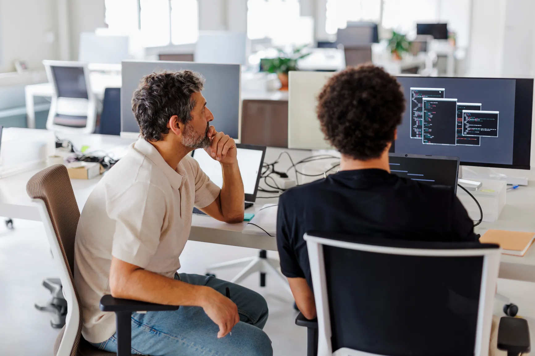 Two software engineers working at monitors in an office