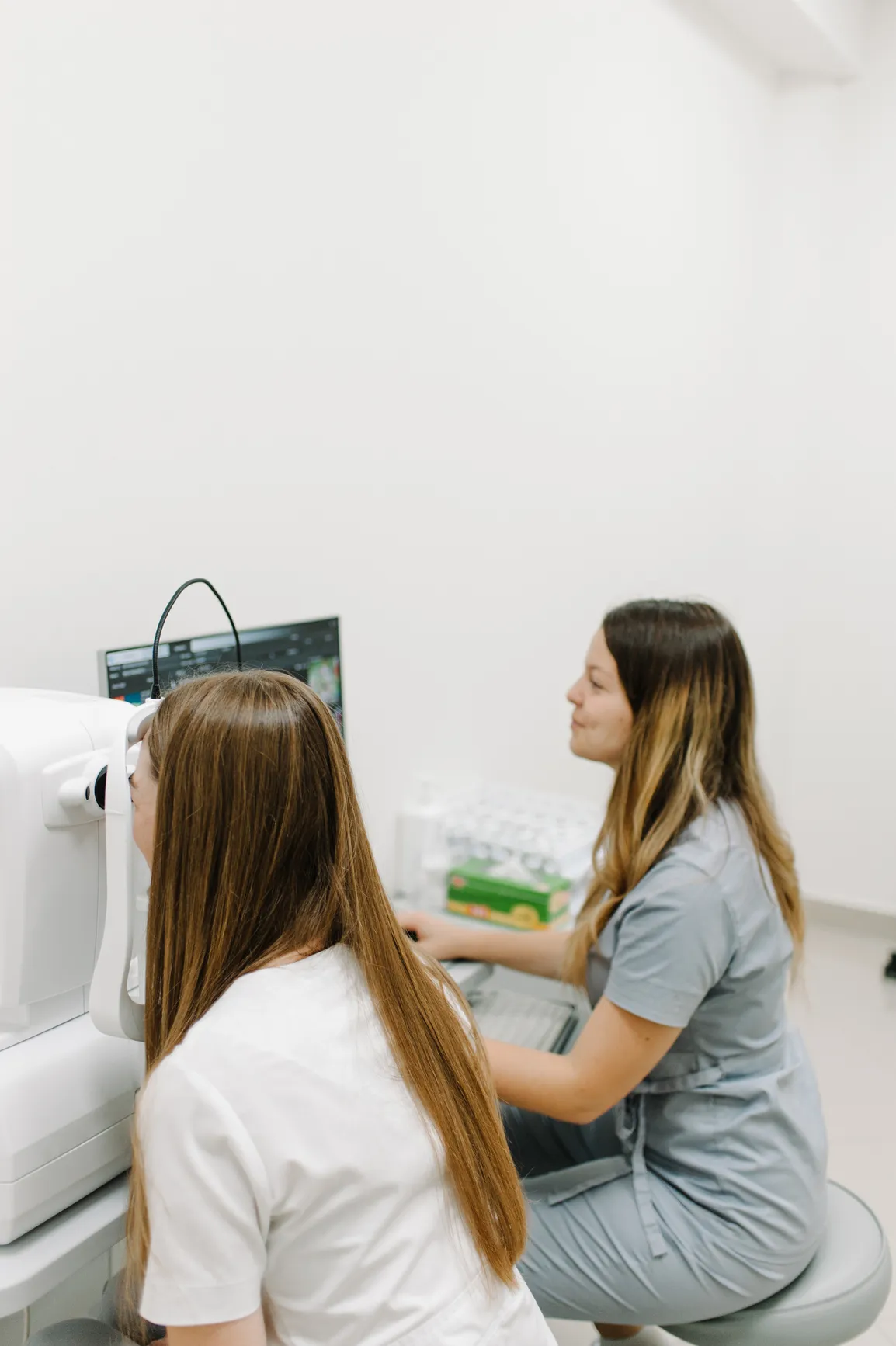 An ophthalmic technician performing an eye scan on a patient