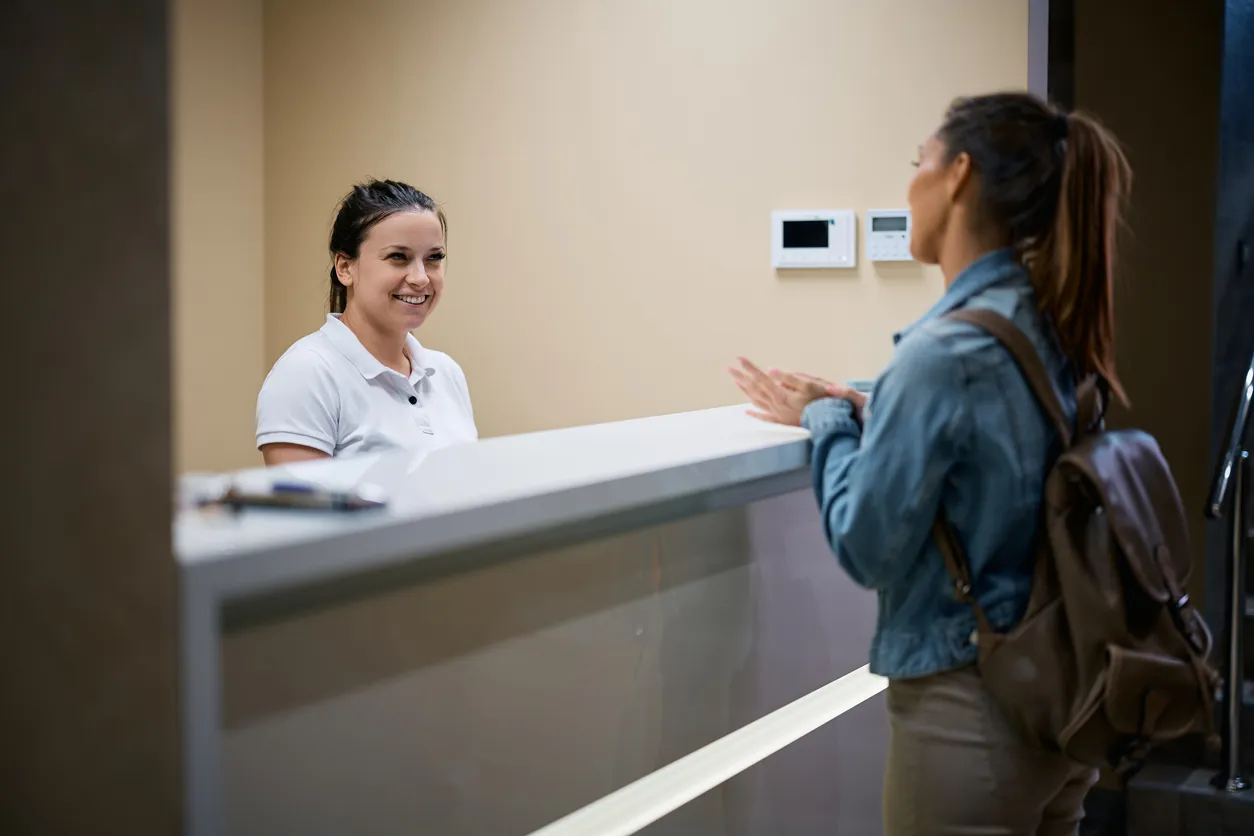 A receptionist greeting a patient at a specialist practice front desk