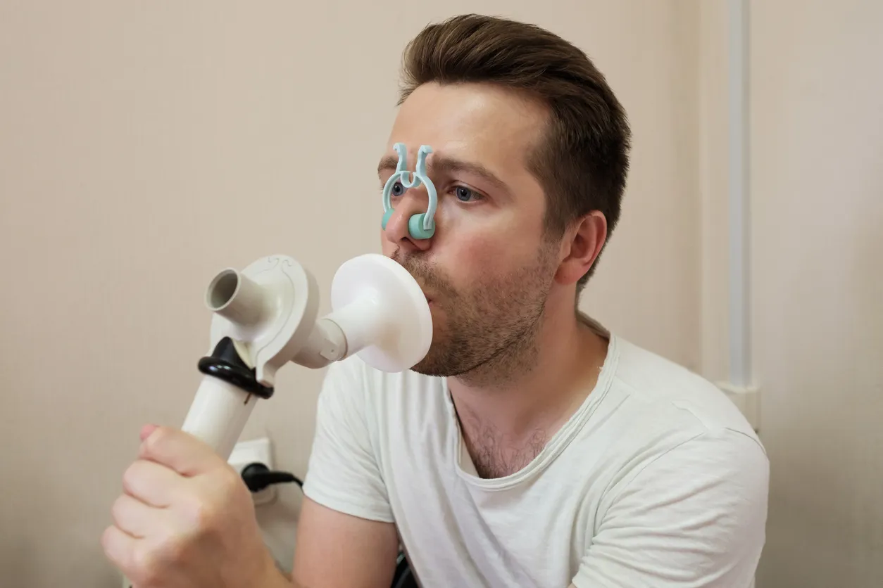 A patient performing a spirometry test with a nose clip and mouthpiece