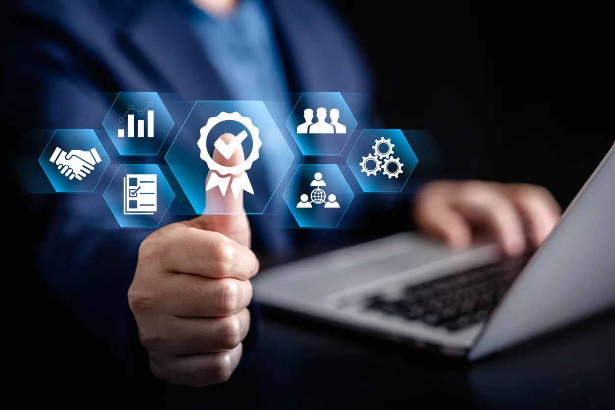 A person using a laptop, overlaid with graphics representing quality standards and certification
