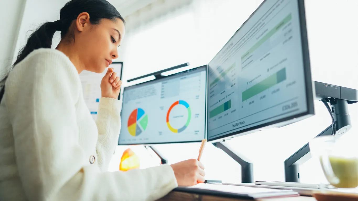 A practice administrator reviewing financial dashboards across two monitors