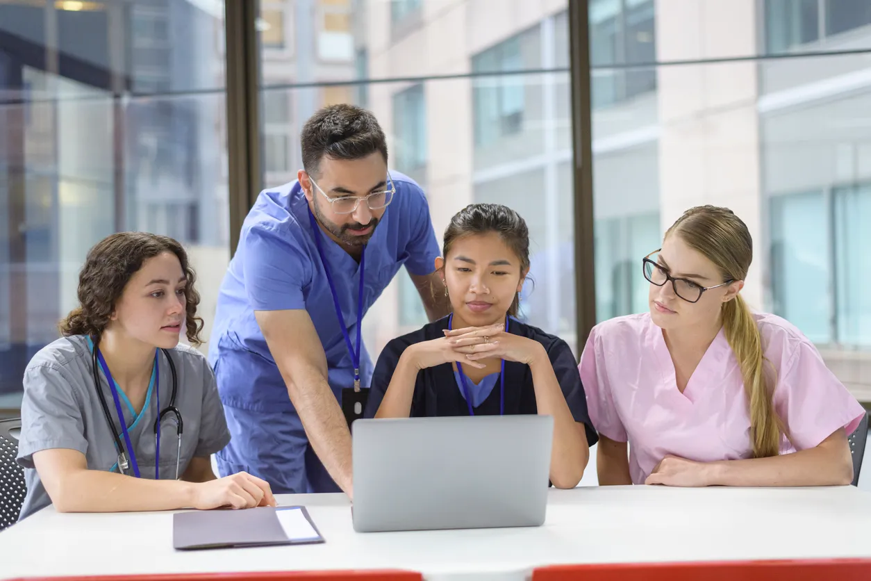 A group of clinicians looking at a laptop together in a meeting room