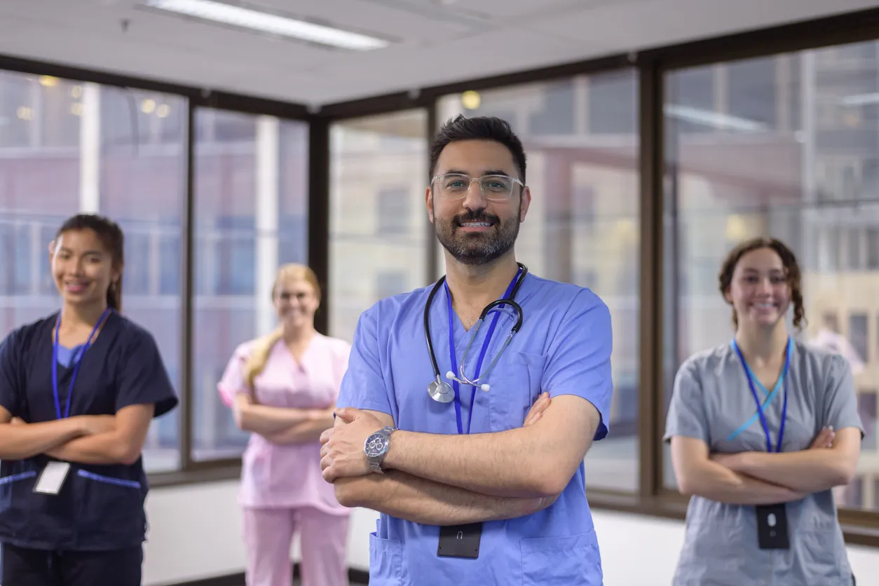 A team of clinicians in scrubs standing together in a hospital office