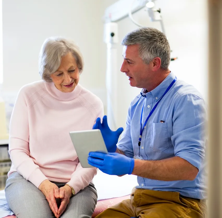 A clinician discussing results on a tablet with an older patient