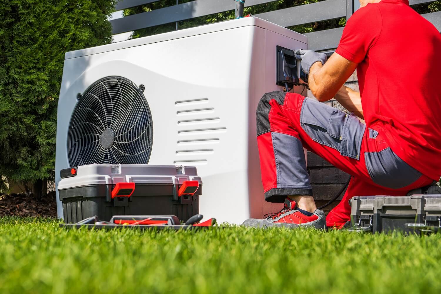 Techniker arbeitet an einer Wärmepumpe im Garten – Alternative zur Heizöl-Heizung im Kontext der CO₂-Steuer auf Heizöl