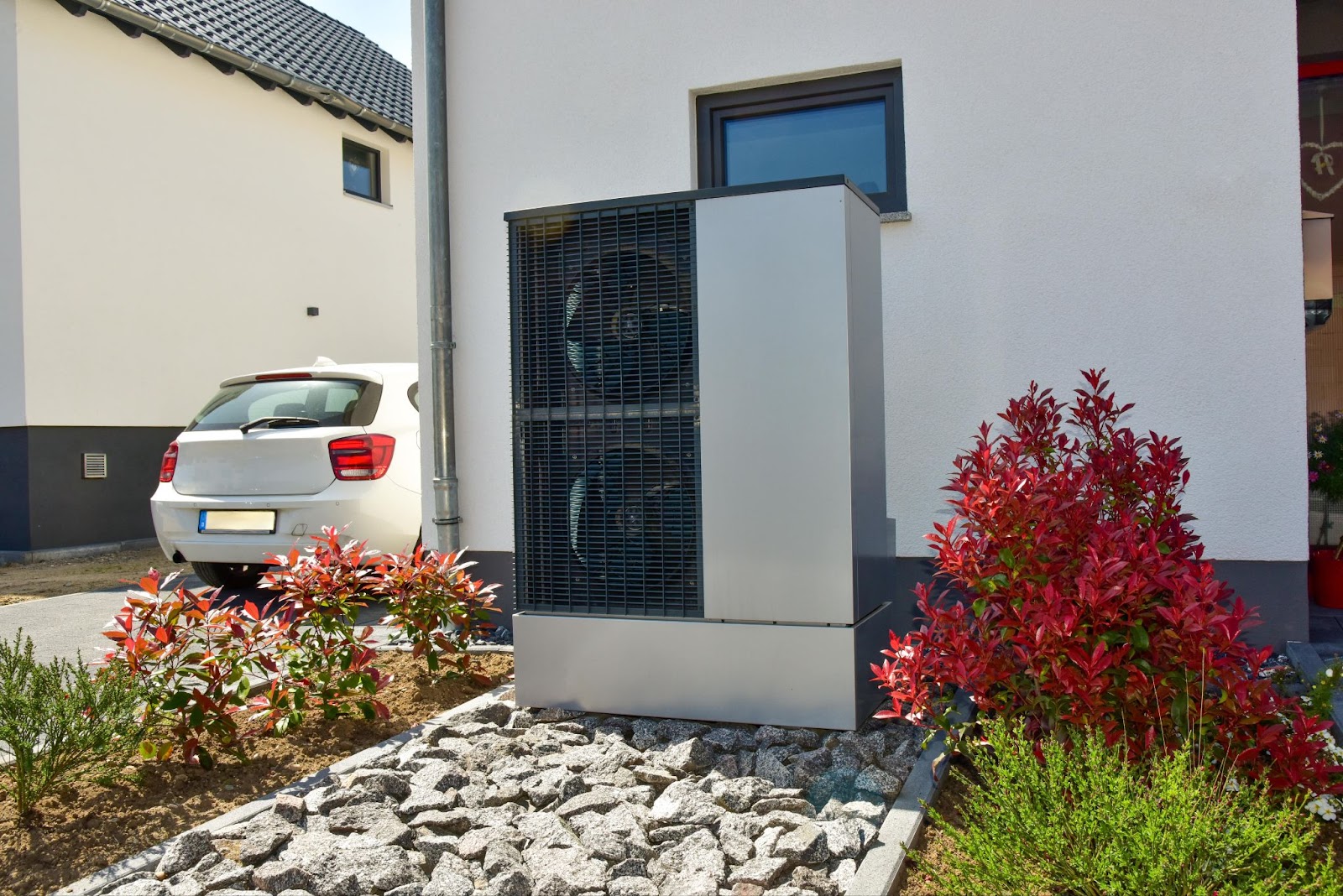 Wärmepumpe vor einem Haus zwischen einem Beet
