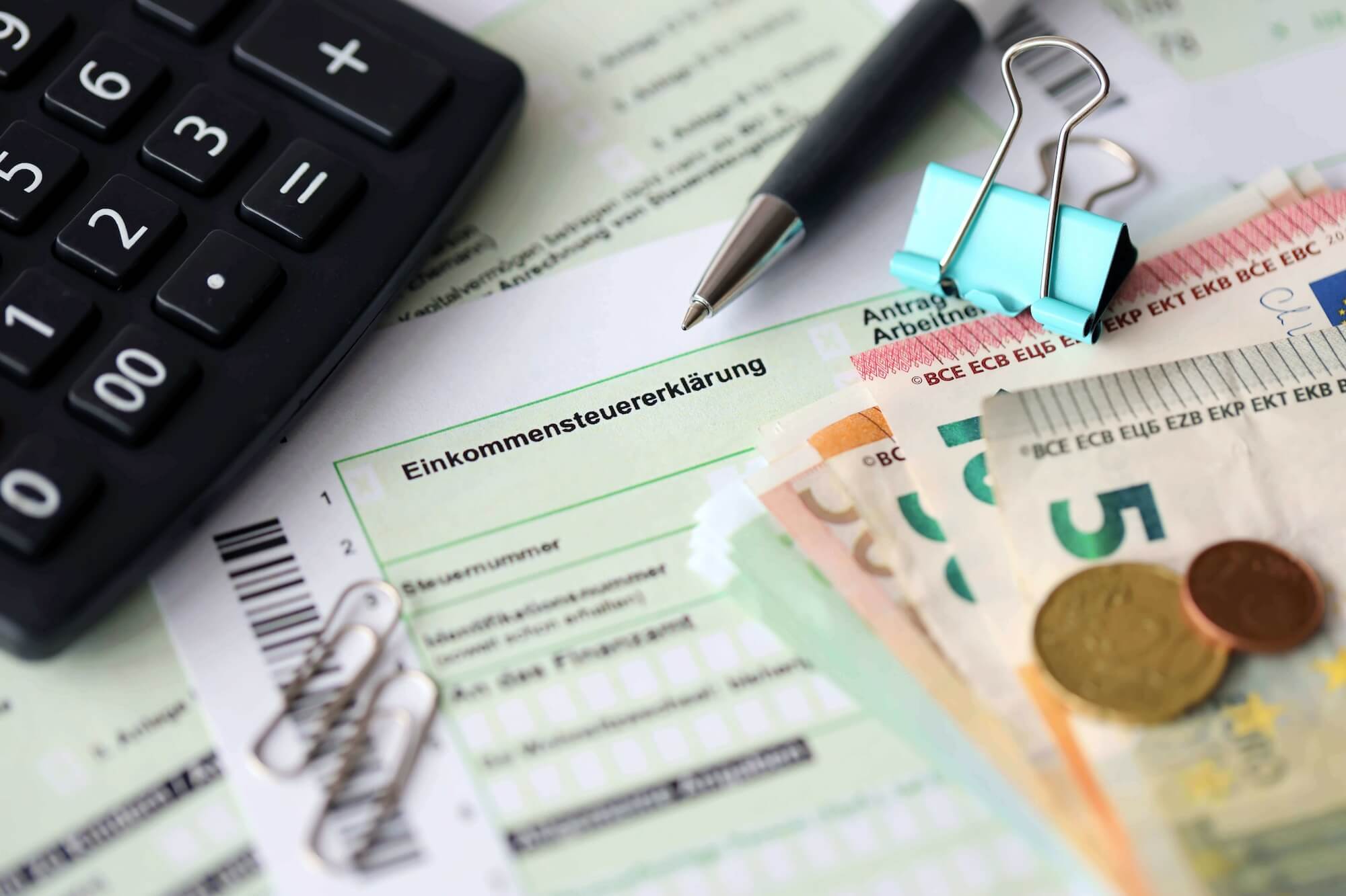 Formular einer Steuererklärung, auf der Schreibmaterial und Bargeld liegt