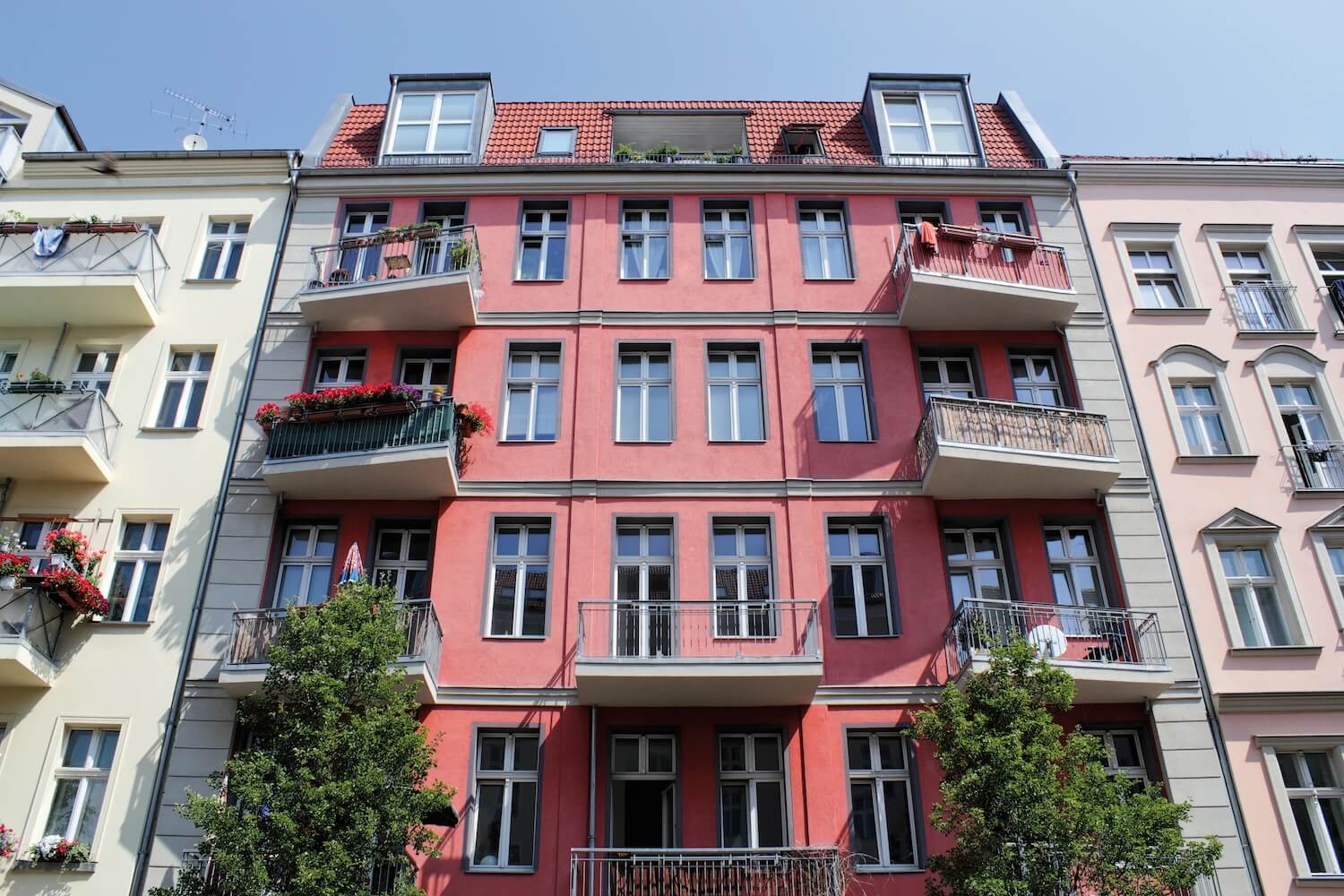 Mehrfamilienhaus mit Balkonen und blühenden Pflanzen, geeignet für die Installation einer Wärmepumpe zur nachhaltigen Wärmeversorgung.
