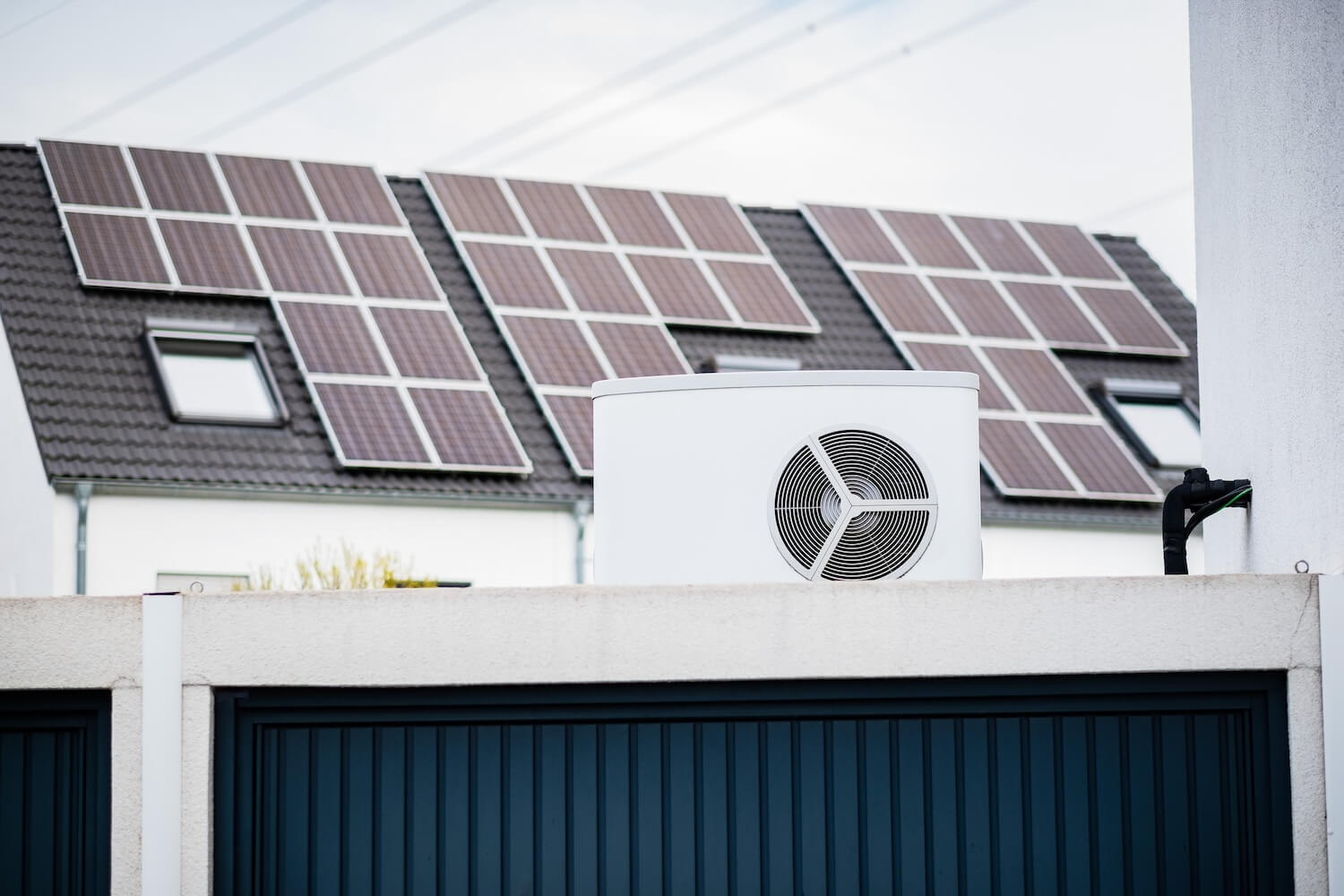 Moderne Wärmepumpe auf Garagendach vor einem Haus mit Solaranlage – Beispiel für nachhaltige Energieversorgung.