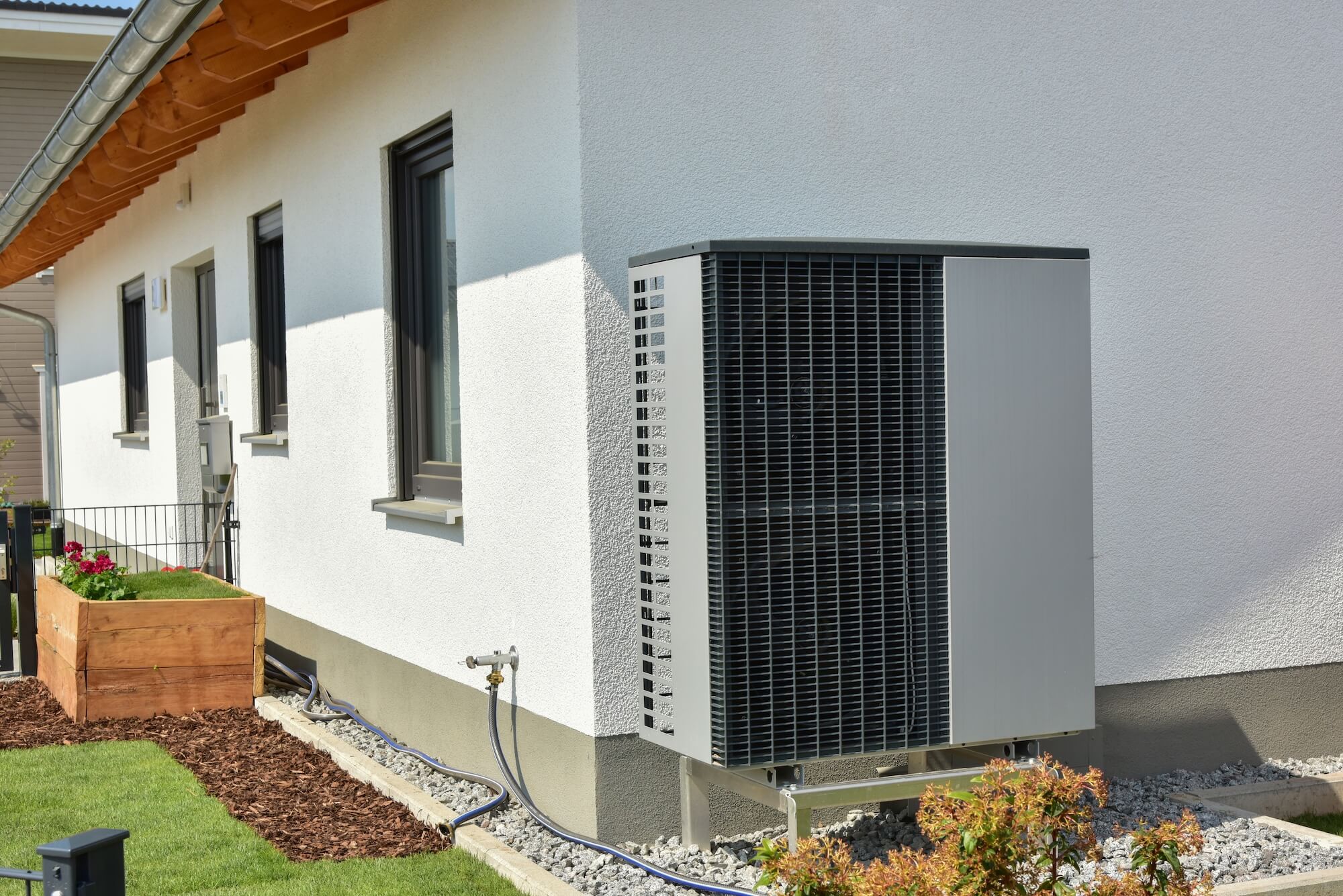 Eine Wärmepumpe mit Schallschutzhaube steht an einer Hauswand.