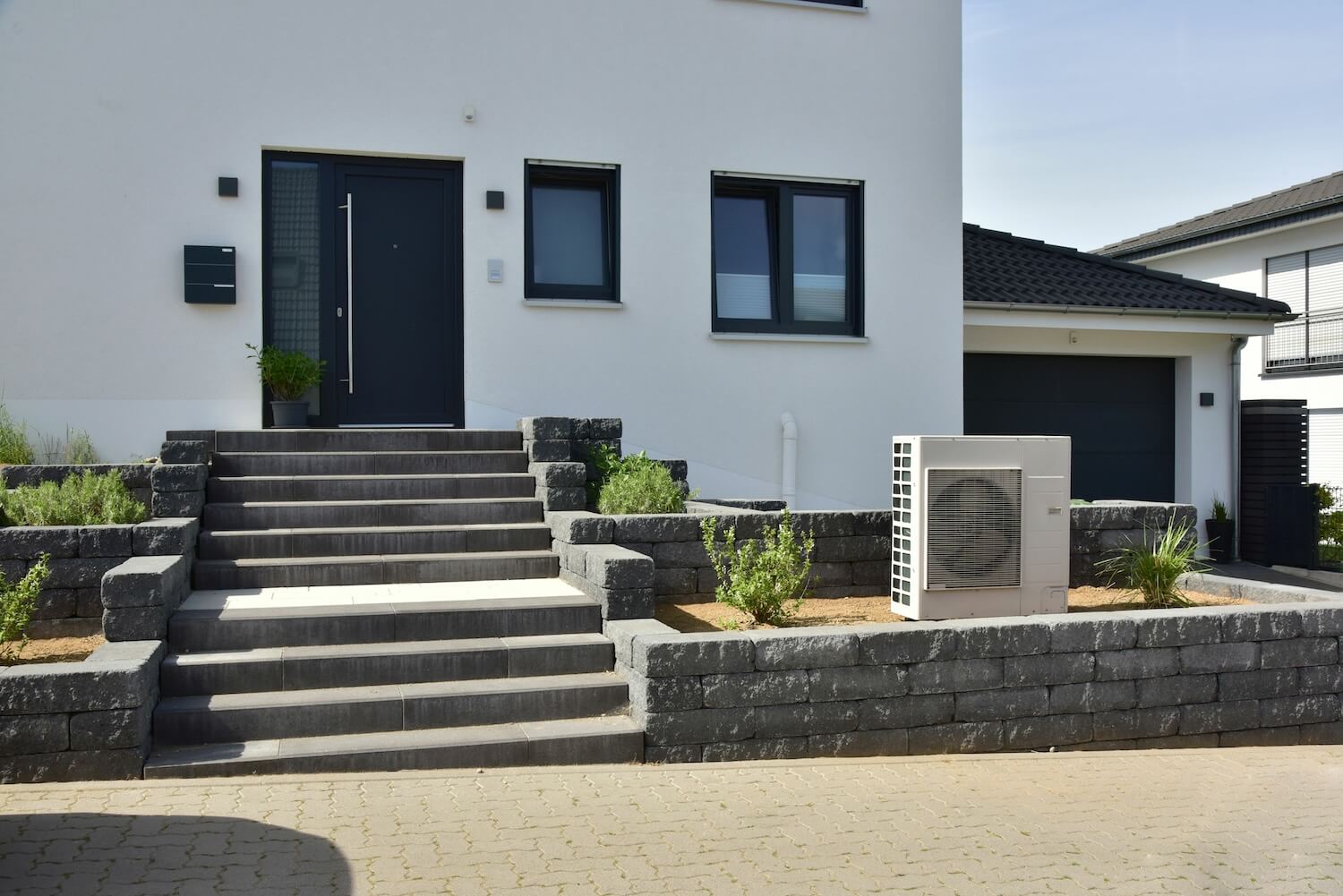Eine mit Propan kühlende Wärmepumpe vor einem weißen Wohnhaus.