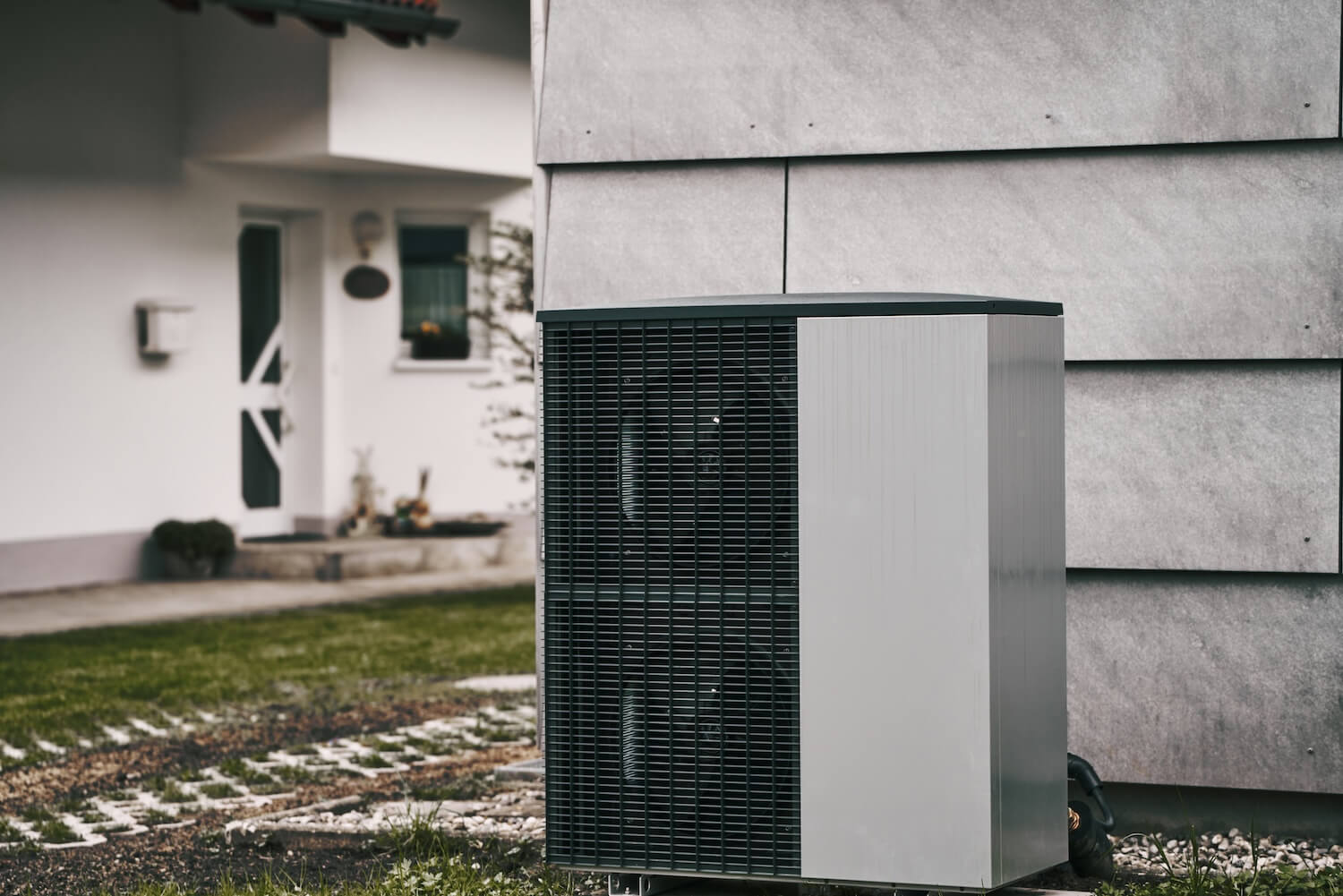 Eine Propan-Wärmepumpe steht an der Hauswand eines Einfamilienhauses.