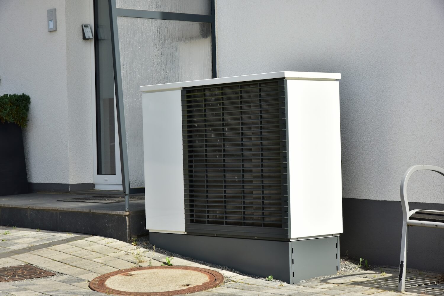 Moderne Wärmepumpe neben einem Hauseingang