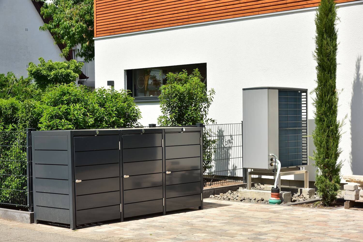 Wärmepumpe mit moderner Abdeckung in einem Vorgarten
