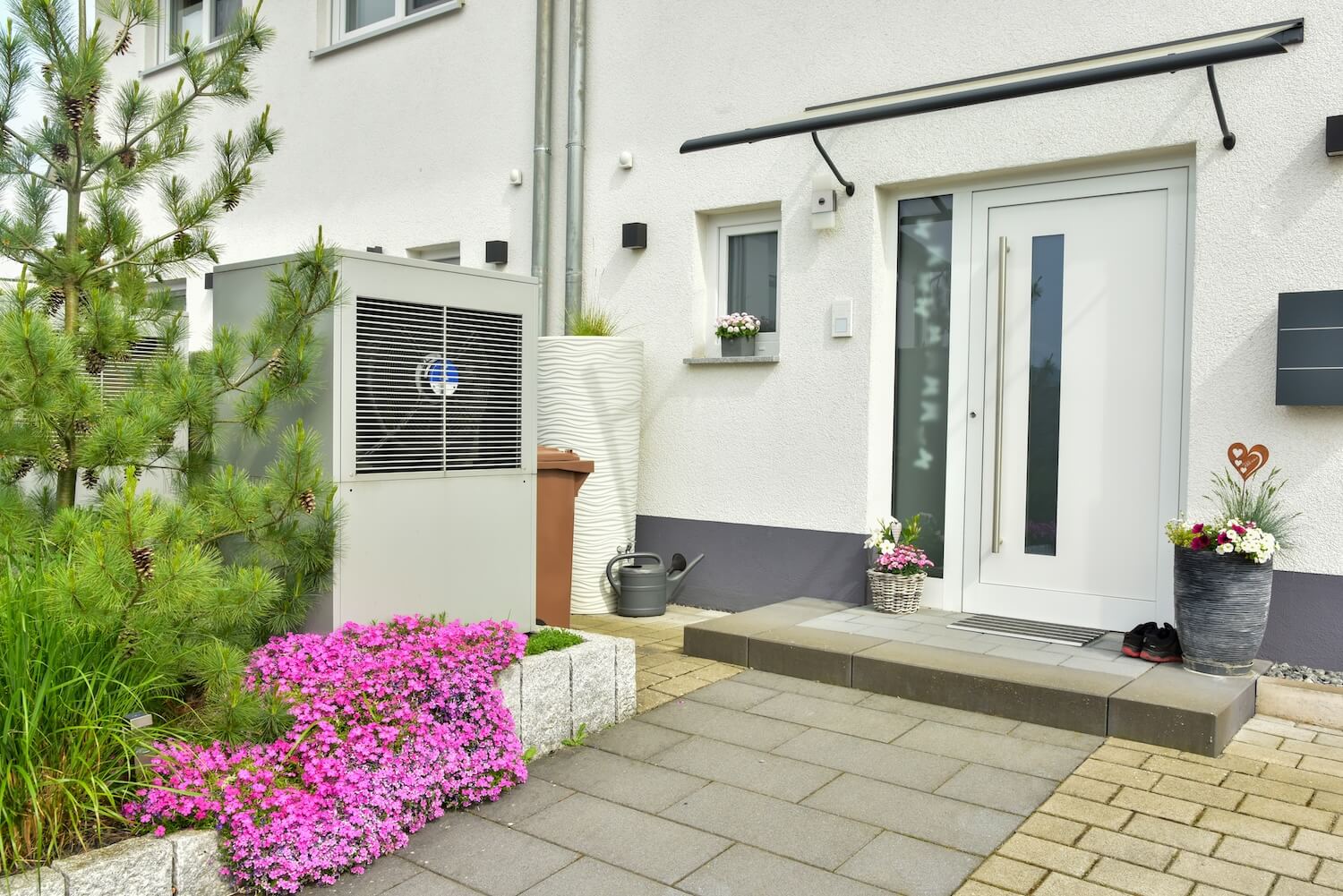 Außeneinheit einer Wärmepumpe vor einem Einfamilienhaus – umweltfreundliche Alternative zur Heizöl-Heizung im Zusammenhang mit der CO₂-Steuer auf Heizöl