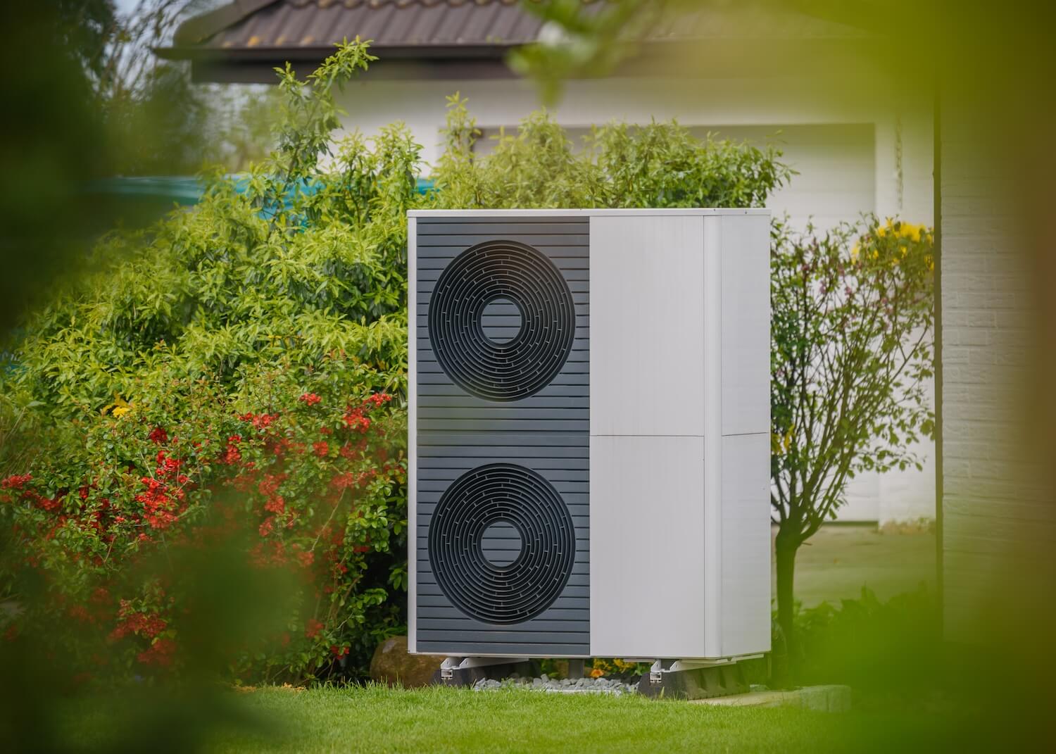Moderne Wärmepumpe mit gutem COP-Wert in einem gepflegten Garten mit grüner Umgebung