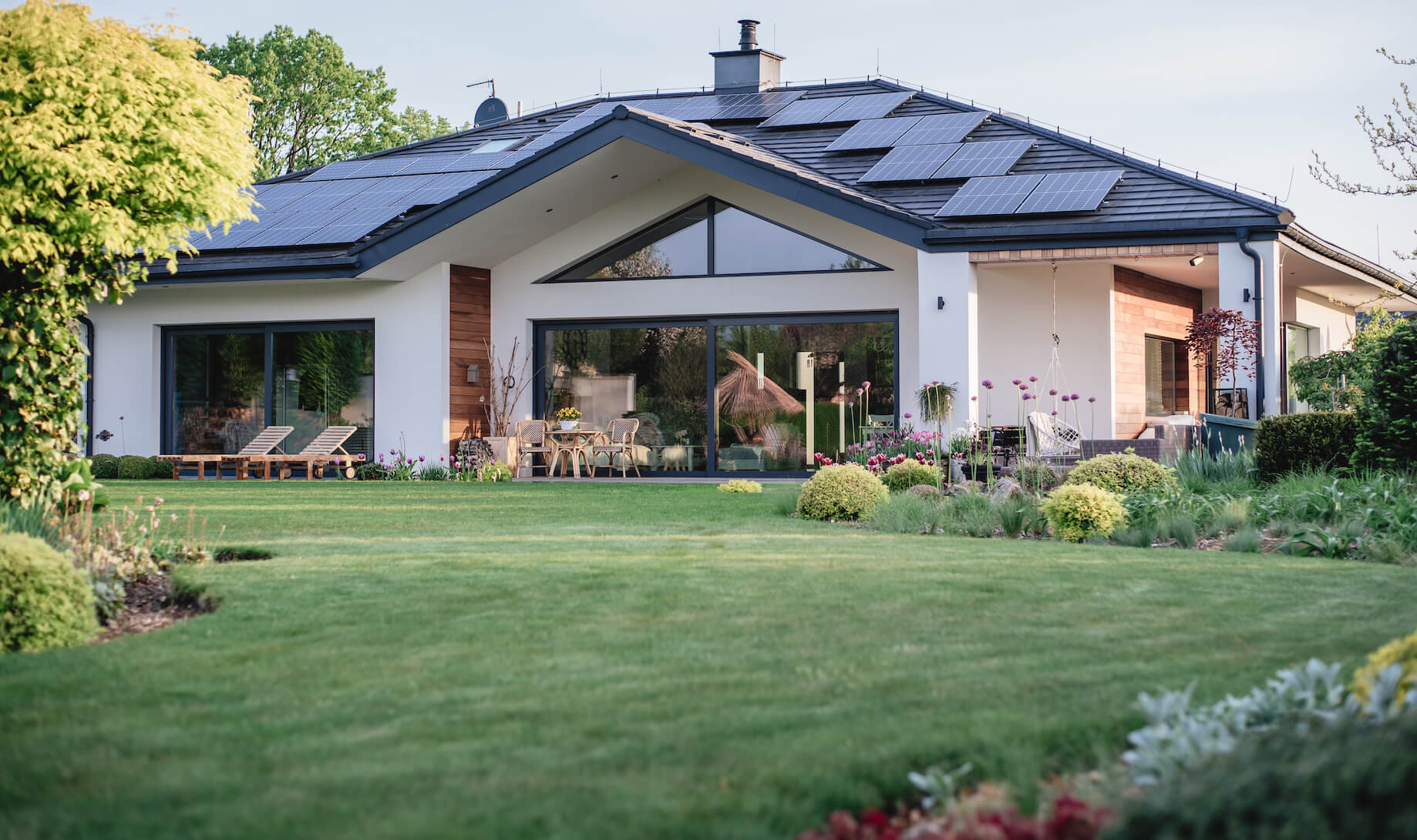 Ansicht auf ein Wohnhaus mit schwarzem Ziegeldach, das mit Photovoltaik-Paneelen bestückt ist.