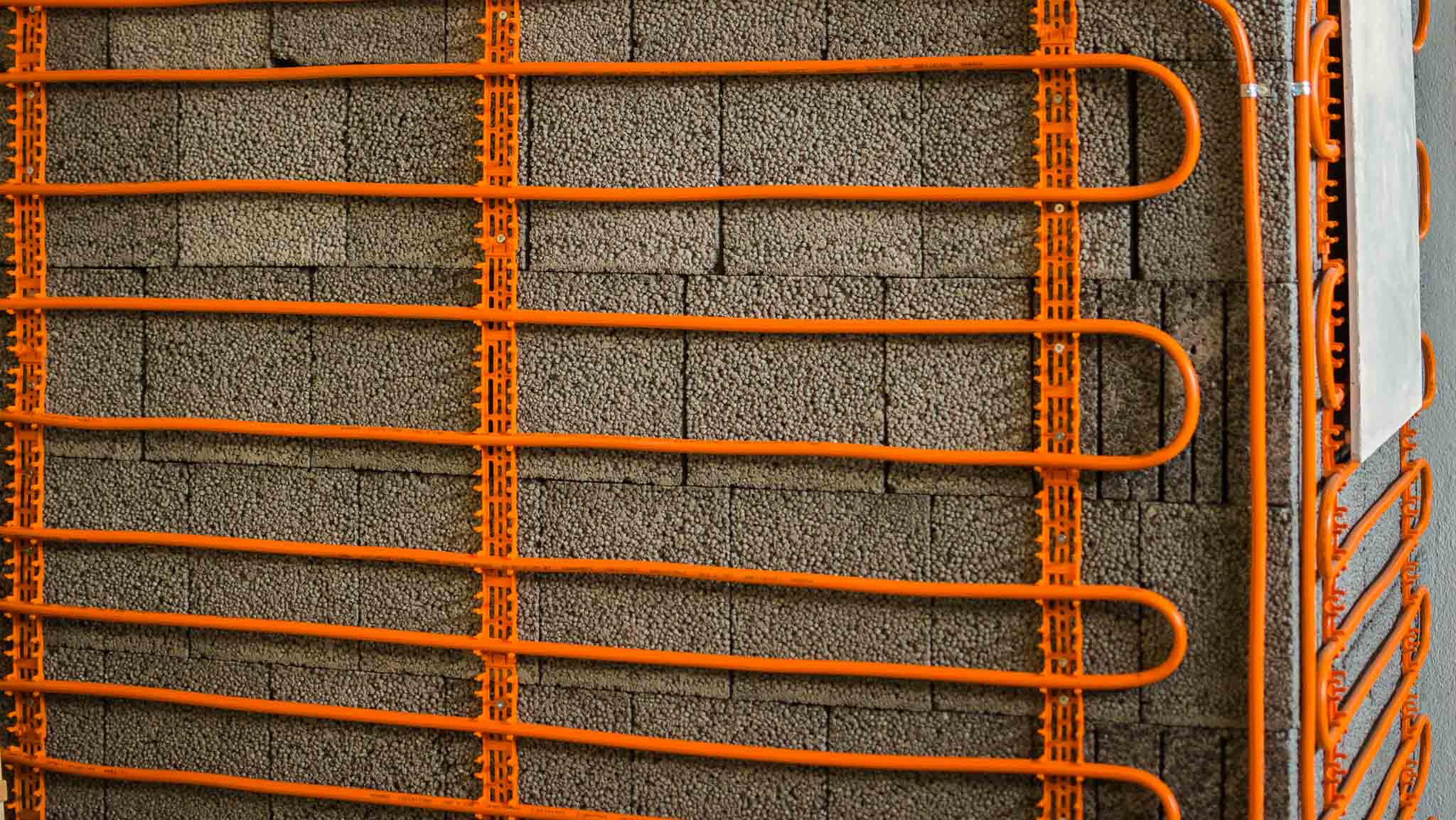 Wandheizung mit orangefarbenen Kühlrohren auf Dämmplatten – Beispiel für alternative Flächenkühlung mit Wärmepumpe.