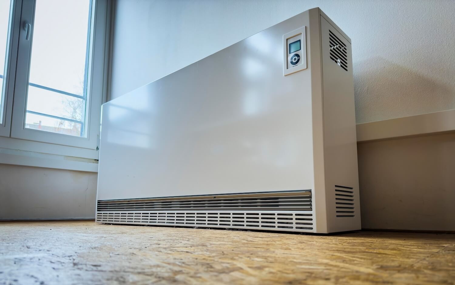 Eine Nachtspeicherheizung steht auf einem Fußboden in einem leeren Zimmer.