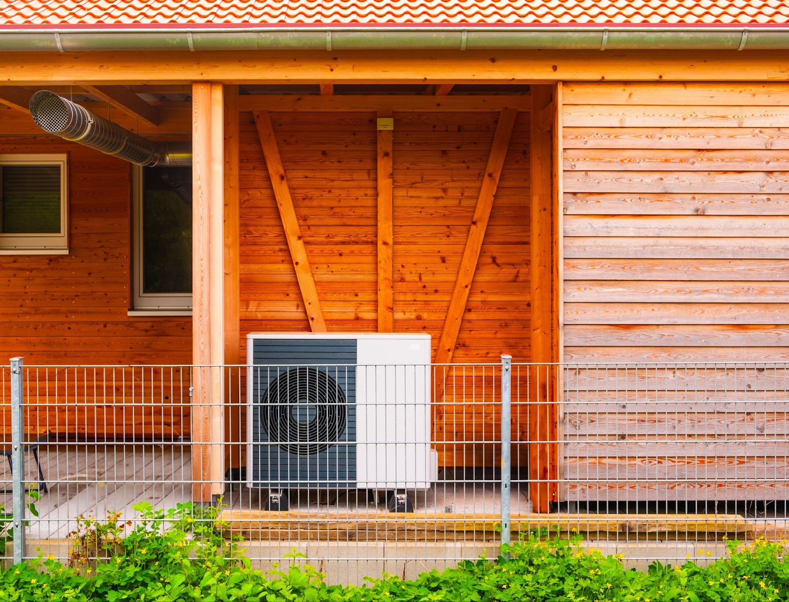 Wärmepumpe vor einem Holzhaus