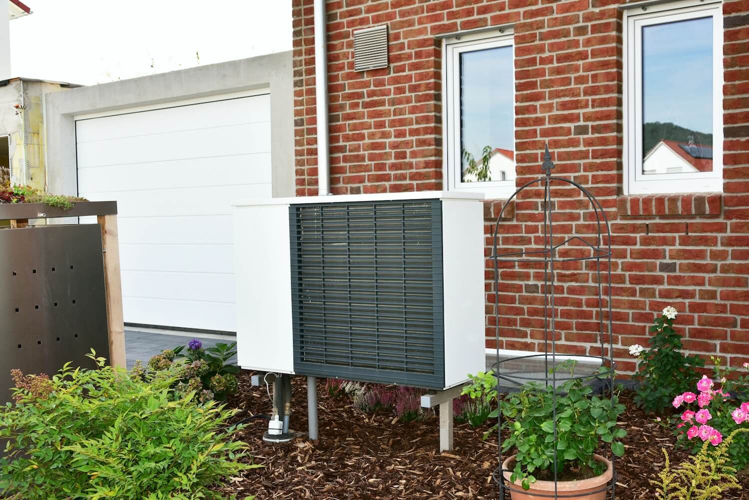 Eine Wärmepumpe steht vor einem Einfamilienhaus.