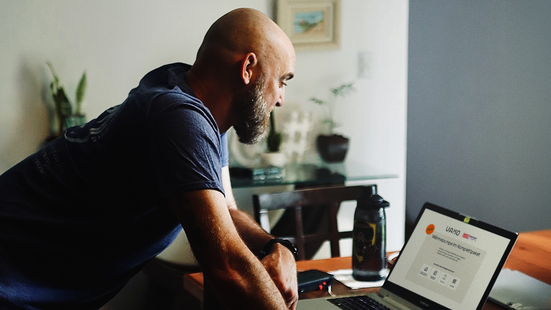 Mann steht vor seinem Laptop mit der Vamo Website auf dem Screen