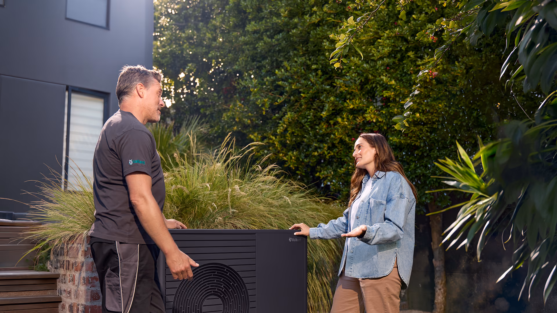 Techniker und Kunde vor der Wärmepumpe im Garten
