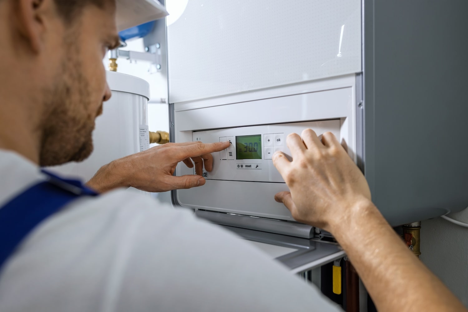 Installateur am Bedienfeld einer Heizung
