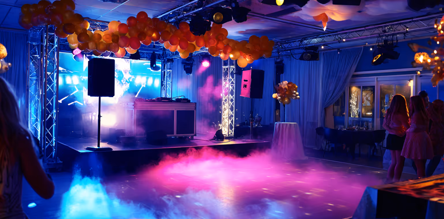Indoor party venue with a DJ stage, colorful balloons, and purple and blue atmospheric lighting and fog effects.